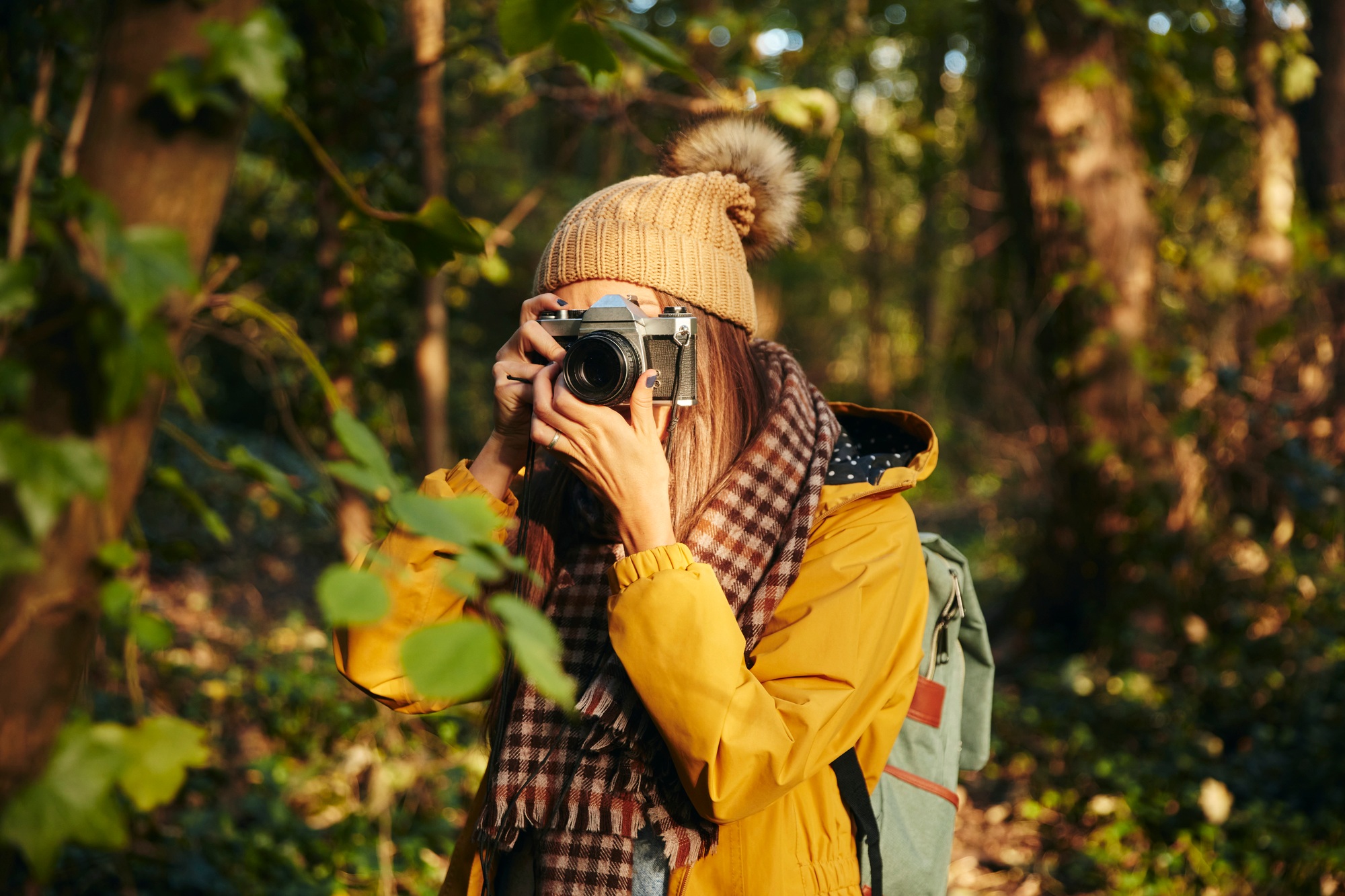 Woman taking photograph with camera in woodland