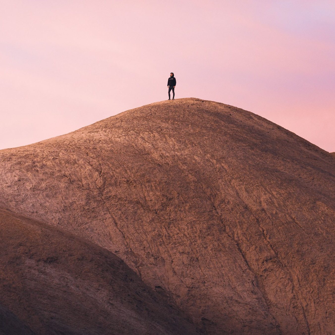 A vertical shot of a man standing in the mountain during sunset
